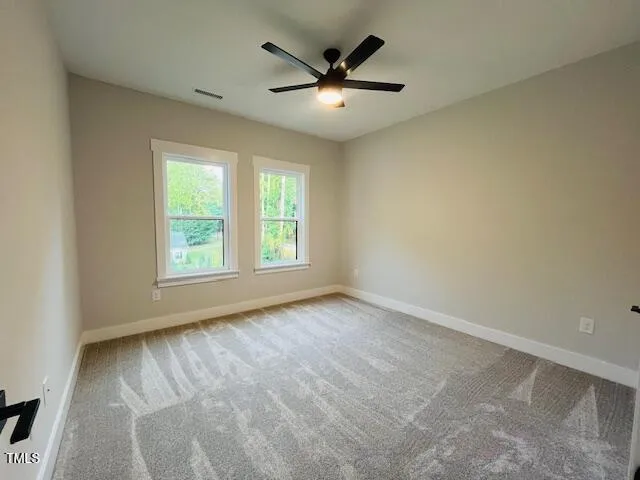an empty room with windows and ceiling fan