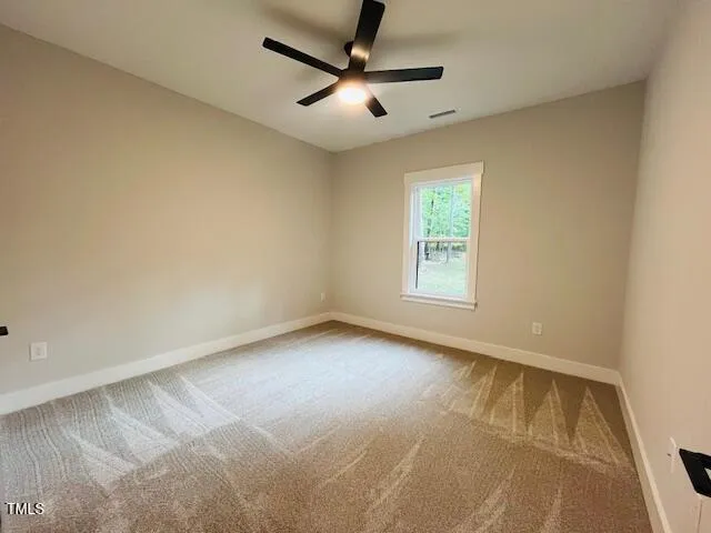 an empty room with window and ceiling fan