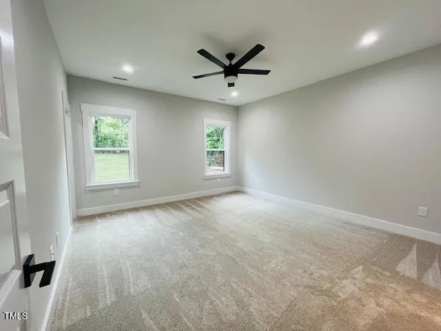 an empty room with windows and fan