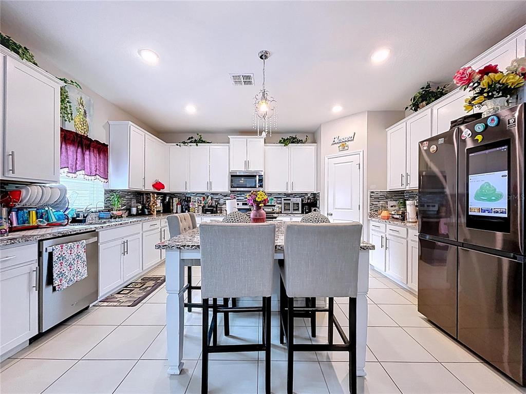 472 6th Avenue Northwest Ruskin, FL 33570 - Photo 21 of 96 a kitchen with stainless steel appliances granite countertop a dining table chairs refrigerator and sink