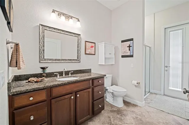 a bathroom with a granite countertop toilet sink and mirror