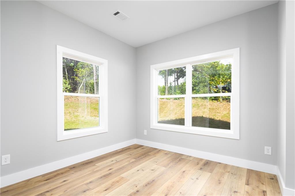 111 Lee Road Phenix City, AL 36867 - Photo 13 of 23 Light wood-finish flooring, two large windows, white trim, and neutral wall tones
