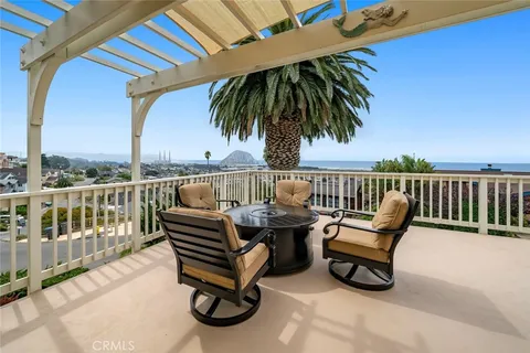 a roof deck with a couple of chairs and a potted plant