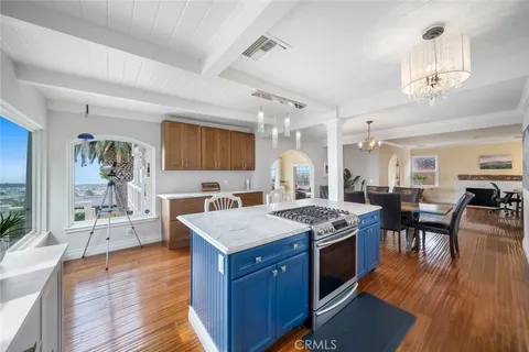 a kitchen with granite countertop a stove top oven a dining table and chairs with wooden floor