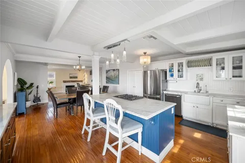 a open kitchen with stainless steel appliances kitchen island granite countertop a table chairs and a refrigerator