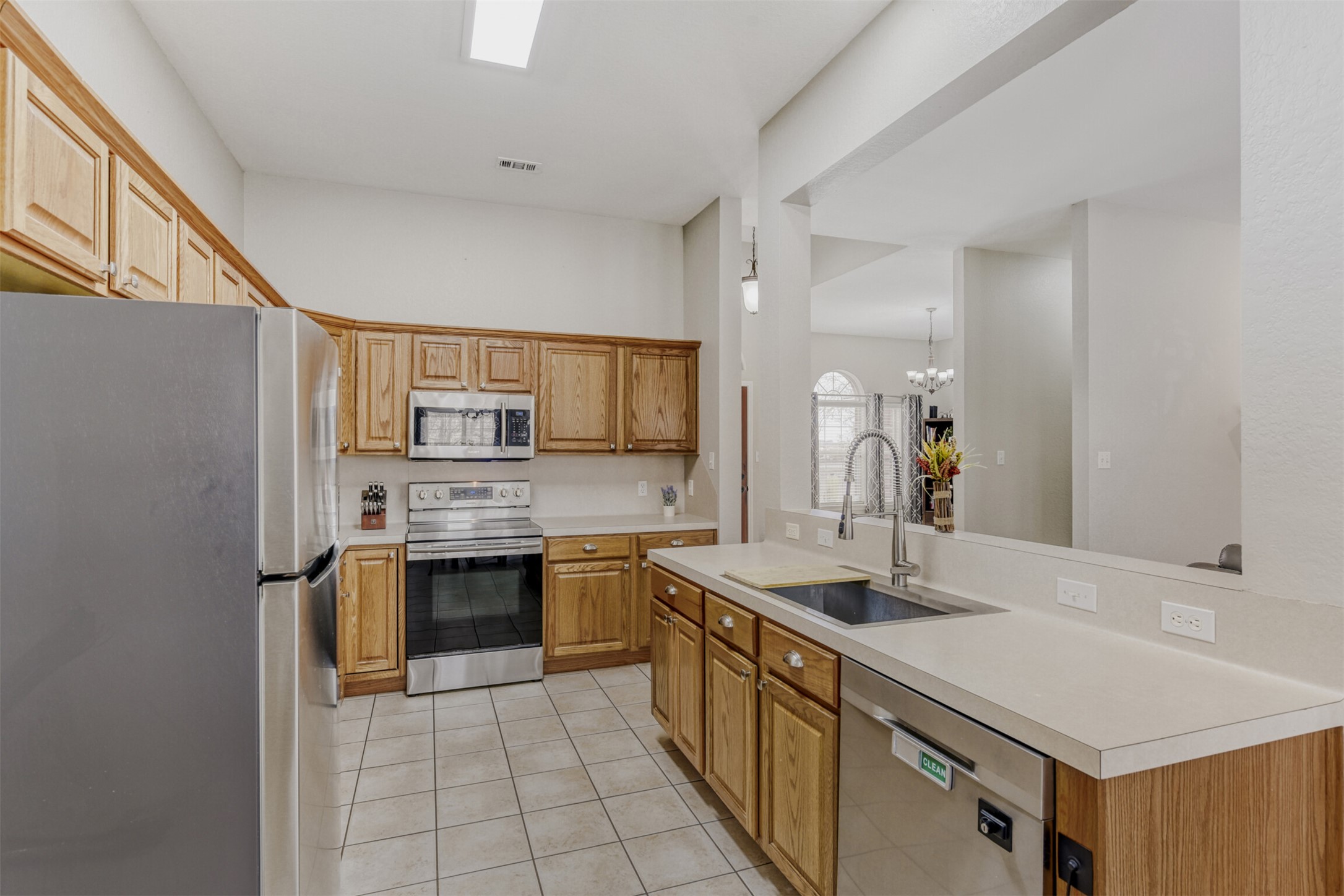 104 Spring Branch Bastrop, TX 78602 - Photo 19 of 32 Kitchen featuring appliances with stainless steel finishes, light countertops, brown cabinets, and light tile patterned floors