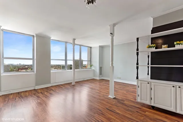 a view of an empty room with a window and wooden floor