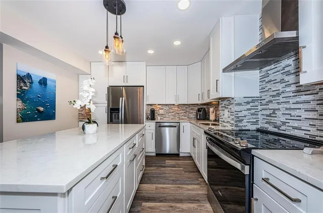 a kitchen with stainless steel appliances granite countertop a sink a stove and a refrigerator
