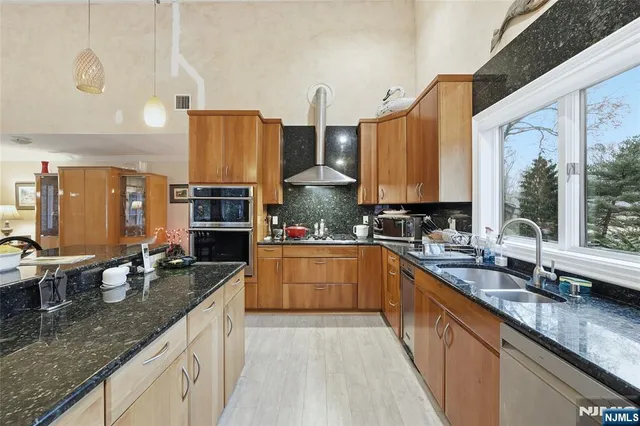 a kitchen with stainless steel appliances granite countertop a sink a stove and a wooden cabinets