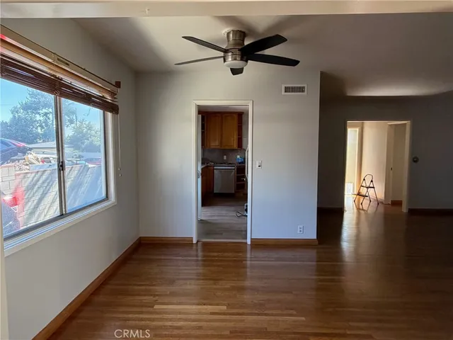 a view of empty room with wooden floor and fan