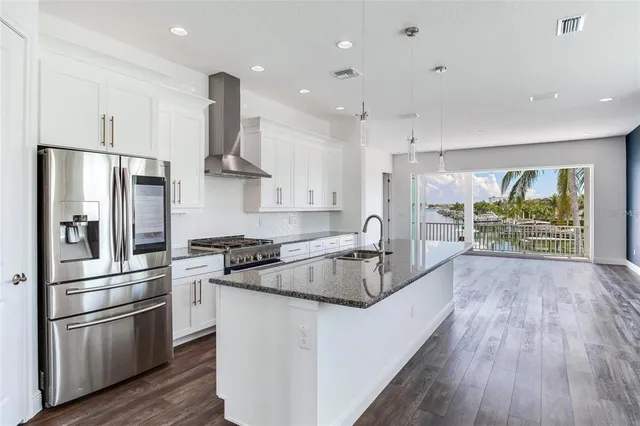 a kitchen with stainless steel appliances granite countertop a refrigerator a stove and a wooden floors