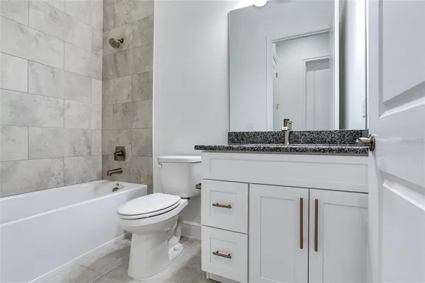a bathroom with a granite countertop sink toilet mirror and bathtub