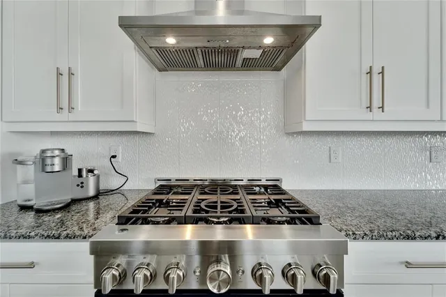 a kitchen with granite countertop stainless steel appliances a stove a sink and cabinets