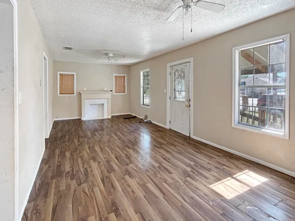 a view of empty room with wooden floor and fan