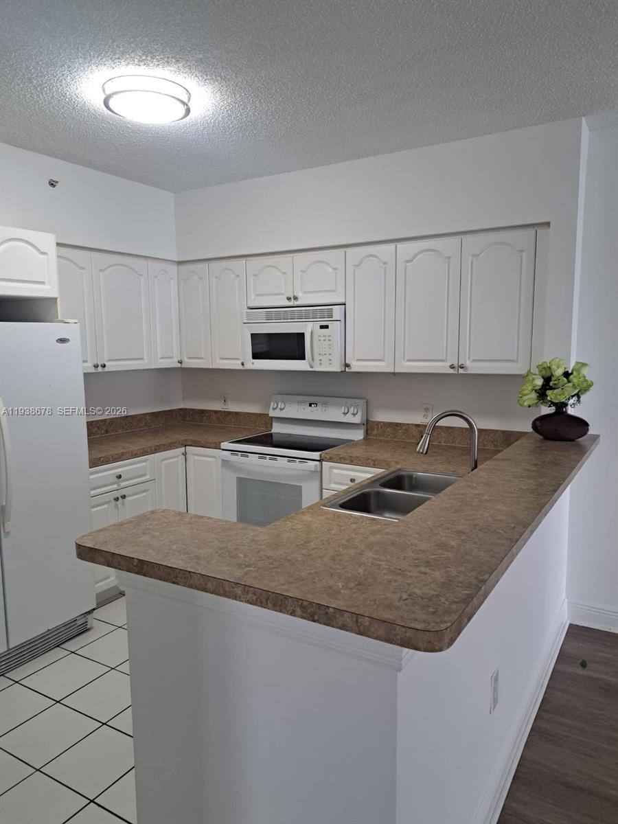 5091 Northwest 7th Street, Unit 1015 Miami, FL 33126 - Photo 4 of 30 a kitchen with stainless steel appliances granite countertop a sink a stove a microwave a refrigerator a counter space and cabinets