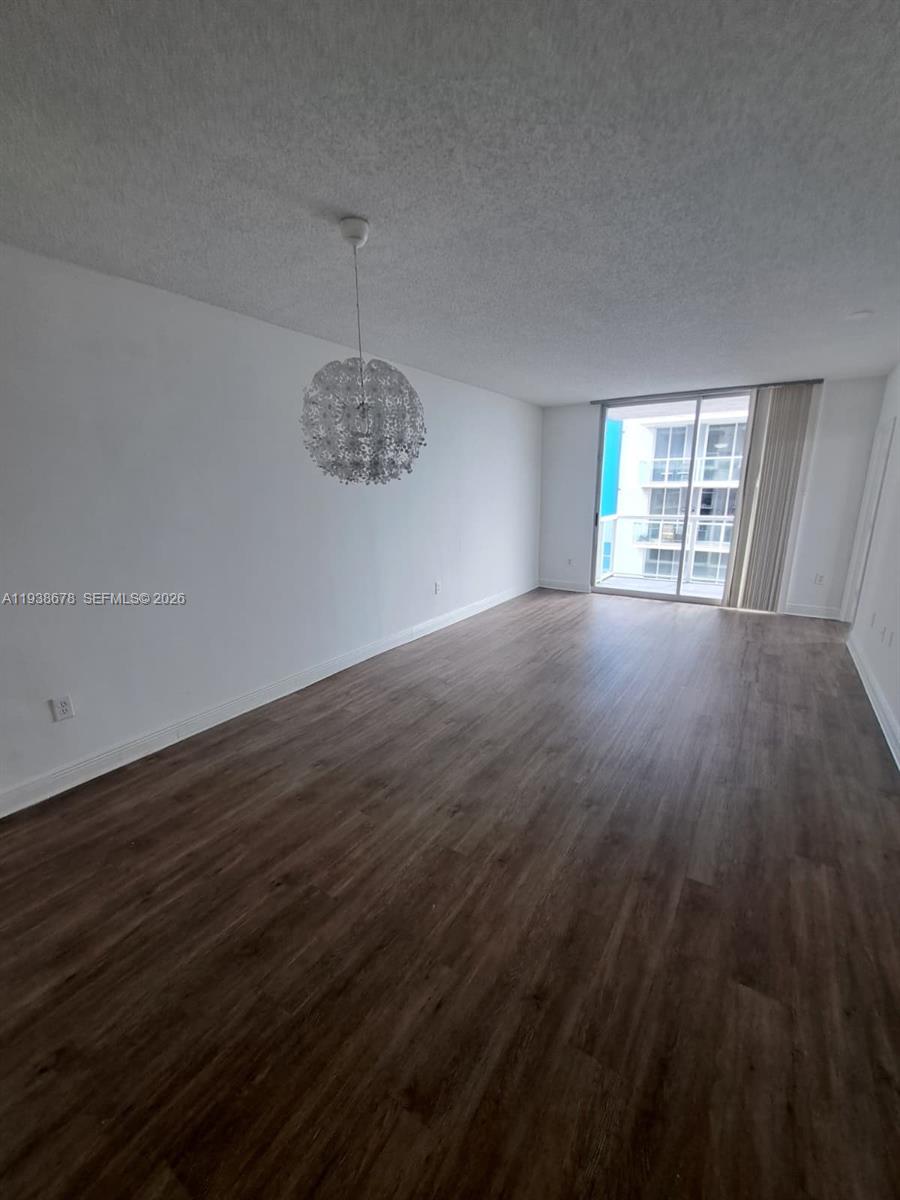 5091 Northwest 7th Street, Unit 1015 Miami, FL 33126 - Photo 5 of 30 an empty room with wooden floor and windows