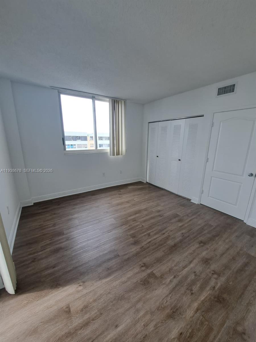 5091 Northwest 7th Street, Unit 1015 Miami, FL 33126 - Photo 6 of 30 a view of an empty room with wooden floor and a window