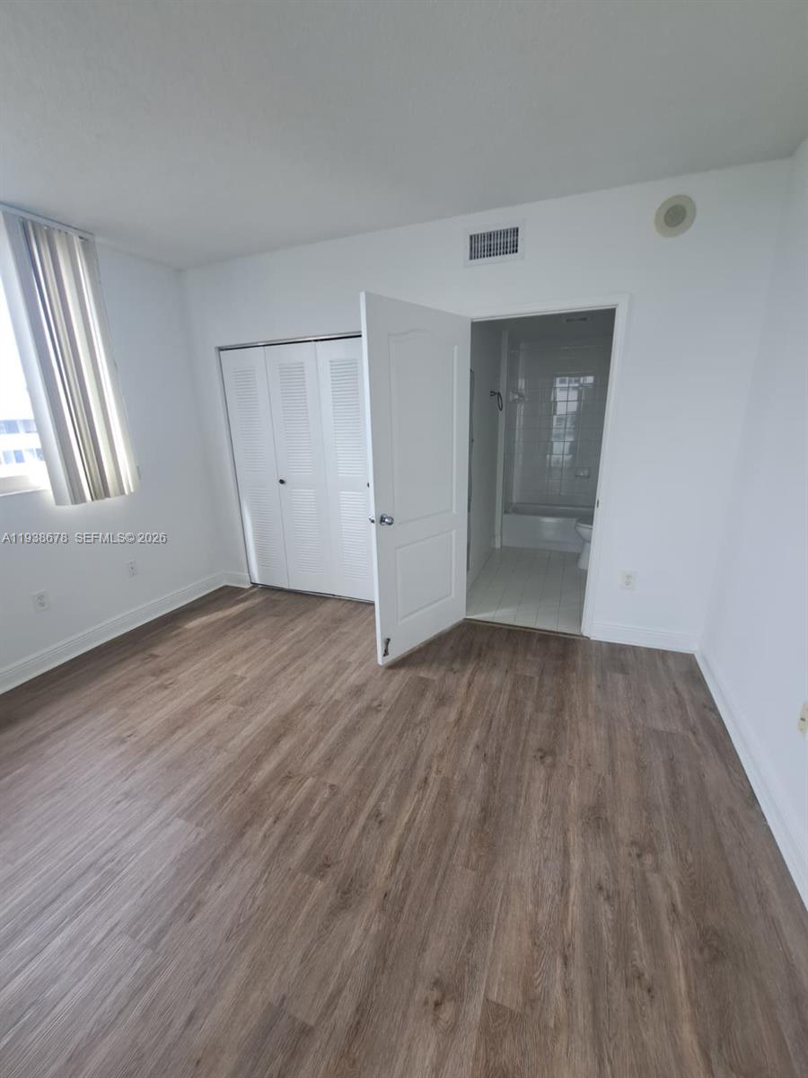 5091 Northwest 7th Street, Unit 1015 Miami, FL 33126 - Photo 7 of 30 an empty room with wooden floor and windows