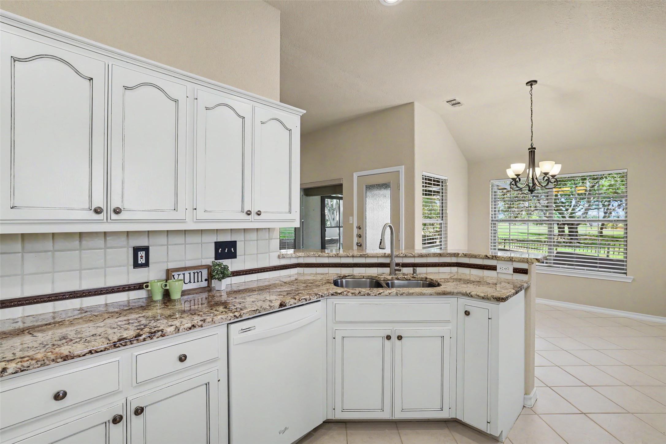 30107 Hamlet Circle Georgetown, TX 78628 - Photo 13 of 40 A chef's kitchen boasts granite counters, white cabinetry, a dishwasher, and a sink, flowing into an adjacent dining space with outdoor views.