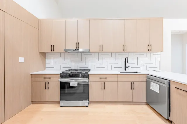 a large kitchen with stainless steel appliances a sink and cabinets