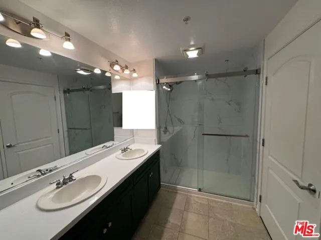 a bathroom with a double vanity sink mirror and shower