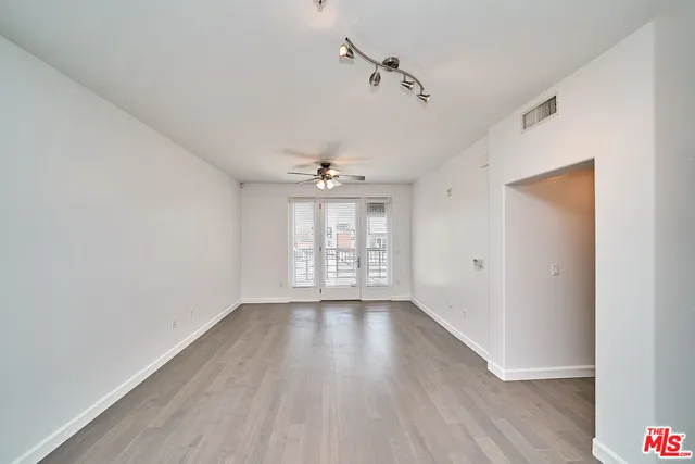 a view of an empty room with a window and wooden floor