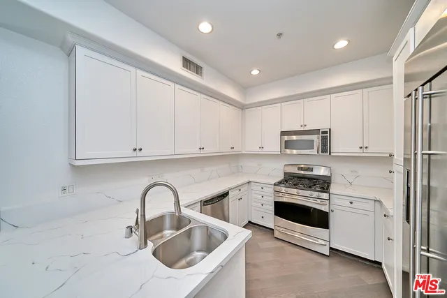 a kitchen with stainless steel appliances granite countertop a sink a stove a refrigerator and cabinets