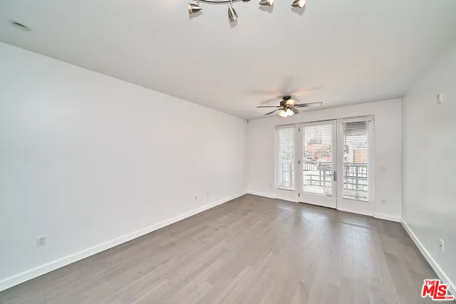 an empty room with wooden floor chandelier fan and windows