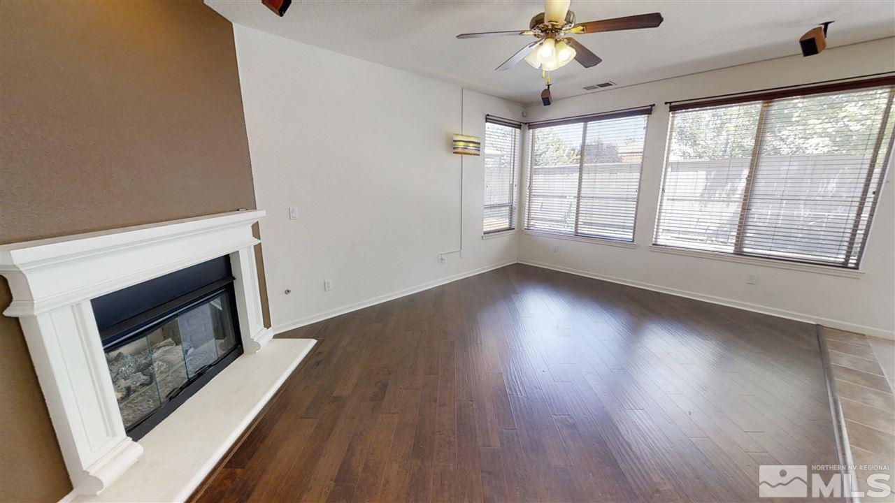 475 Silver Bridle Court Reno, NV 89521 - Photo 7 of 35 a view of an empty room with wooden floor fireplace and a window