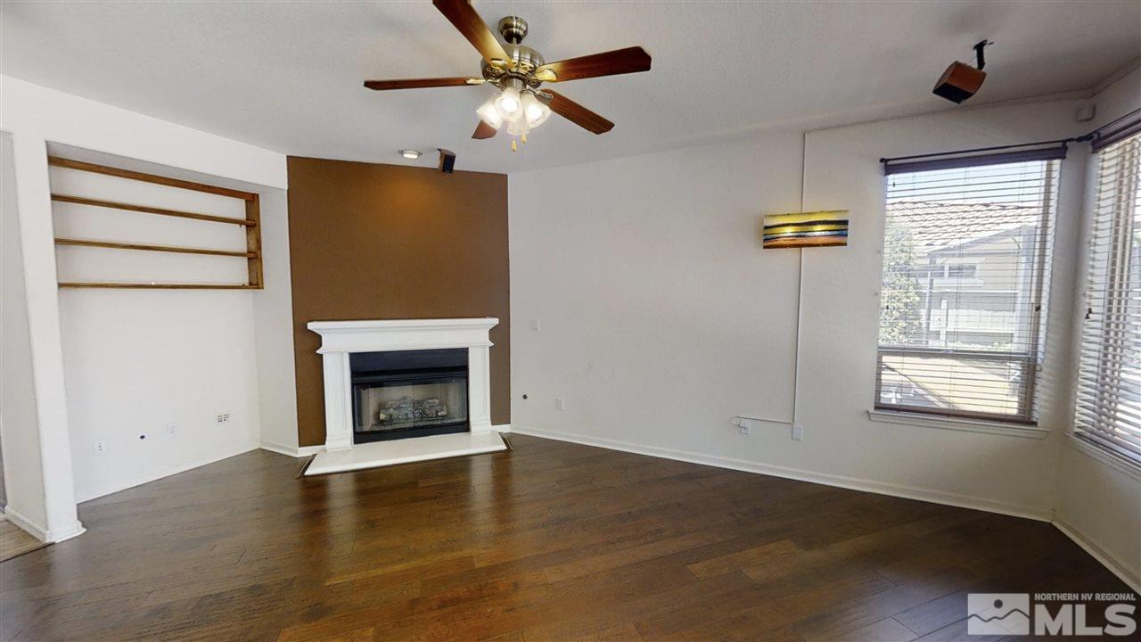 475 Silver Bridle Court Reno, NV 89521 - Photo 8 of 35 an empty room with windows a fireplace a ceiling fan and wooden floor