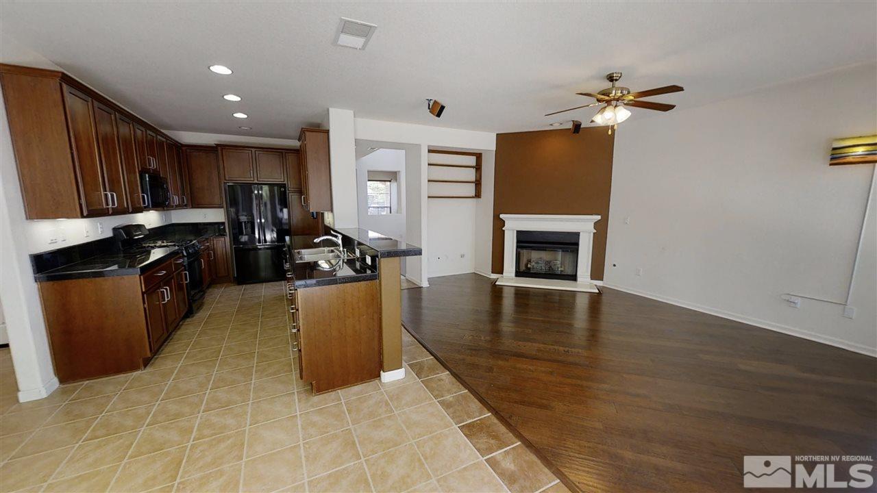 475 Silver Bridle Court Reno, NV 89521 - Photo 10 of 35 a kitchen with granite countertop stainless steel appliances a stove refrigerator a sink a microwave oven with wooden floor and cabinets