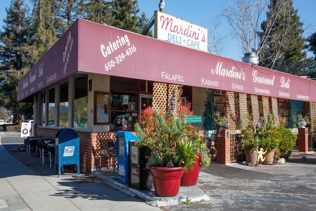 a front view of a building with lots of potted plants