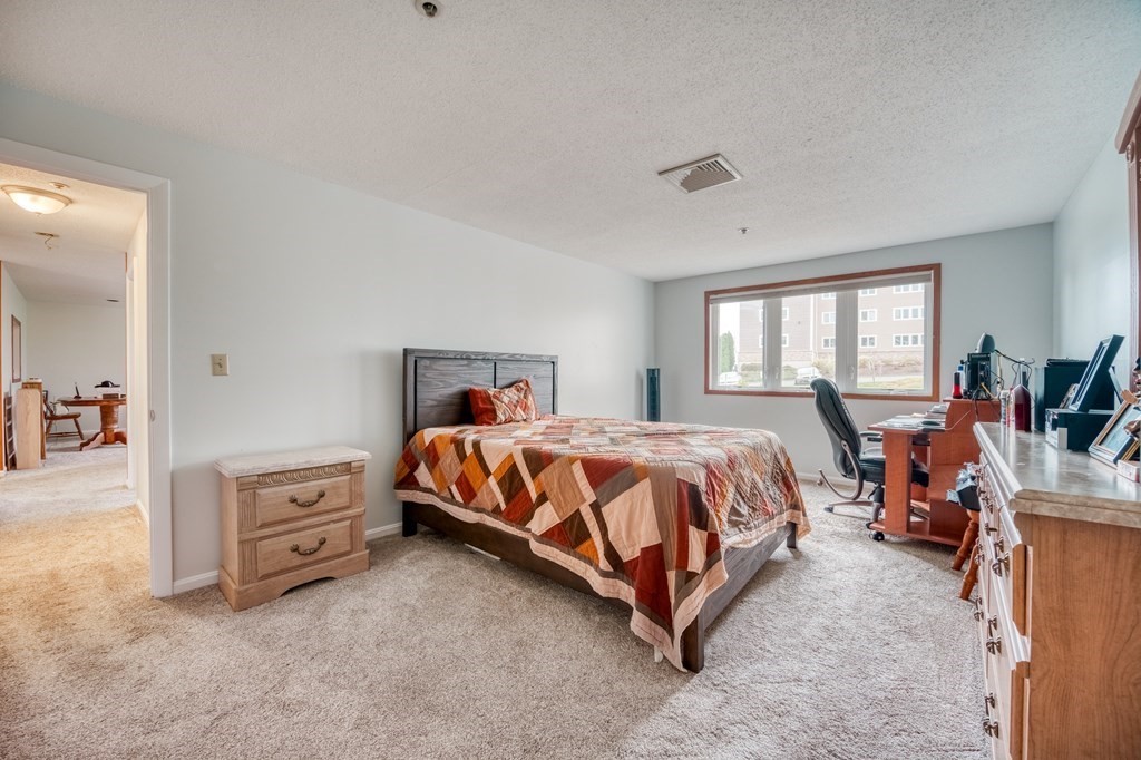 38 Dunham Road, Unit 108 Beverly, MA 01915 - Photo 13 of 30 a spacious bedroom with a bed and dresser