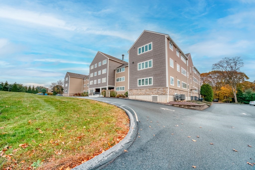 38 Dunham Road, Unit 108 Beverly, MA 01915 - Photo 28 of 30 a front view of a residential apartment building with a yard and parking space