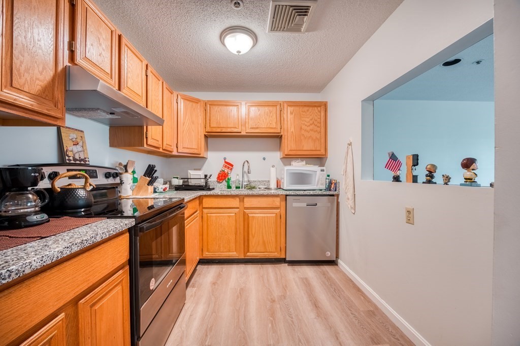 38 Dunham Road, Unit 108 Beverly, MA 01915 - Photo 8 of 30 a kitchen with granite countertop stainless steel appliances a sink a counter space and cabinets