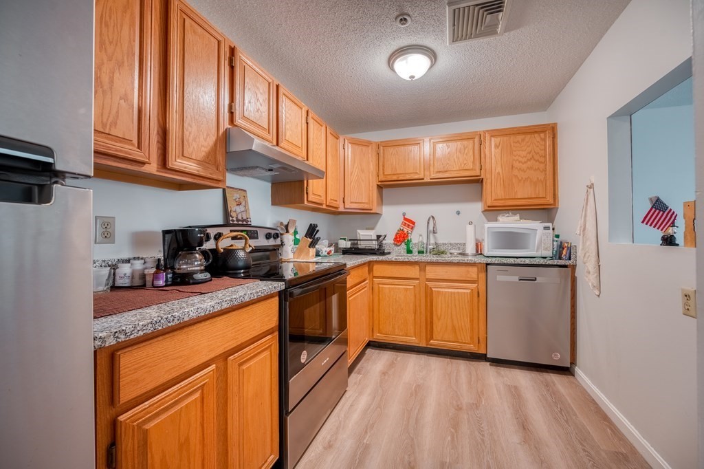 38 Dunham Road, Unit 108 Beverly, MA 01915 - Photo 9 of 30 a kitchen with stainless steel appliances granite countertop a stove a sink dishwasher and a refrigerator