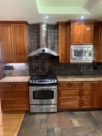 a kitchen with stainless steel appliances granite countertop wooden cabinets and a stove top oven