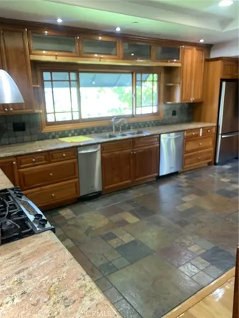 a kitchen with stainless steel appliances granite countertop a sink a stove and a granite counter tops with a large window