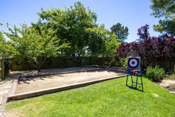 a sign board with a yard and trees in the background