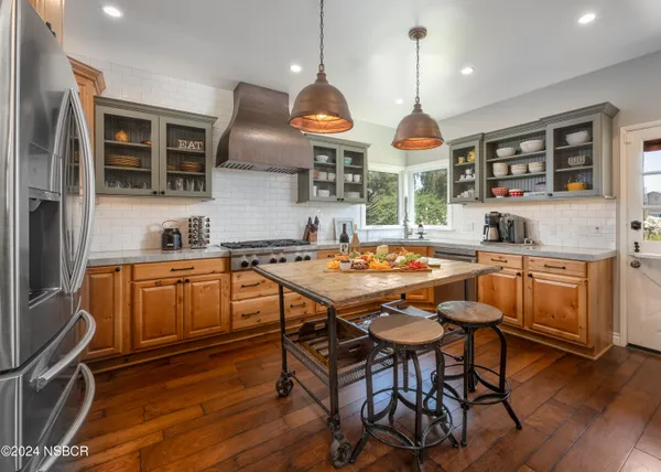 a kitchen with stainless steel appliances granite countertop a stove a sink dishwasher a dining table and chairs with wooden floor