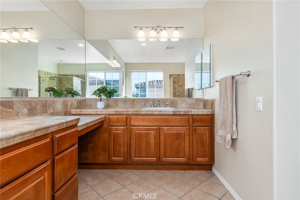 34641 Irwin Street Beaumont, CA 92223 - Photo 37 of 63 a bathroom with a granite countertop sink a mirror and a shower