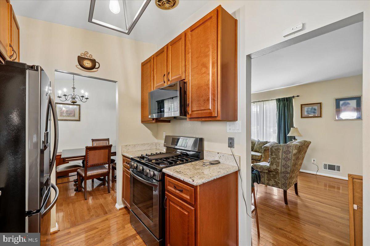 5001 Aspen Hill Road Rockville, MD 20853 - Photo 17 of 68 a kitchen with stainless steel appliances granite countertop a stove top oven a refrigerator a dining table and chairs with wooden floor
