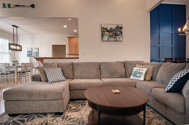 a living room with furniture kitchen view and a large window