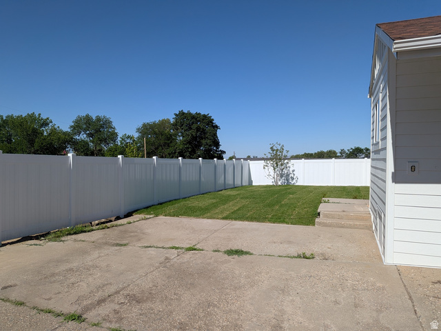 360 400 North Centerville, UT 84014 - Photo 9 of 30 Expansive backyard featuring a white privacy fence, manicured lawn, concrete patio area, and white siding exterior