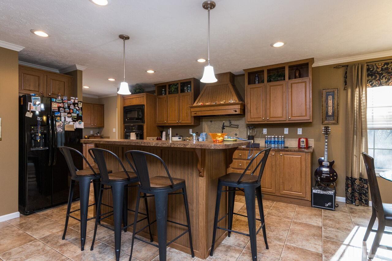 175 Williams Road Spring Hope, NC 27882 - Photo 8 of 30 a kitchen with stainless steel appliances kitchen island granite countertop a refrigerator a stove a sink a dining table and chairs with wooden floor