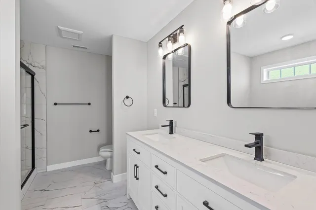 a bathroom with a double vanity sink mirror and toilet