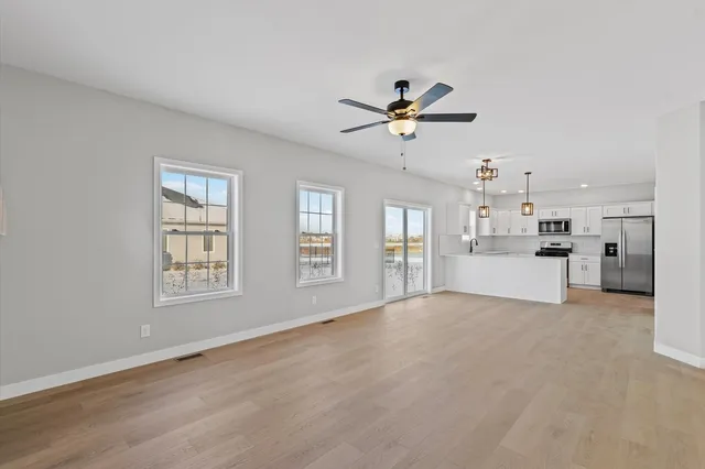 a view of an empty room with a kitchen and a window