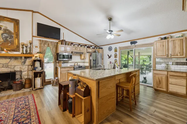a open kitchen with stainless steel appliances granite countertop a stove oven a dining table and chairs with wooden floor