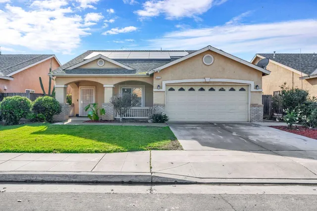 a view of a white house with a small yard and a large parking space