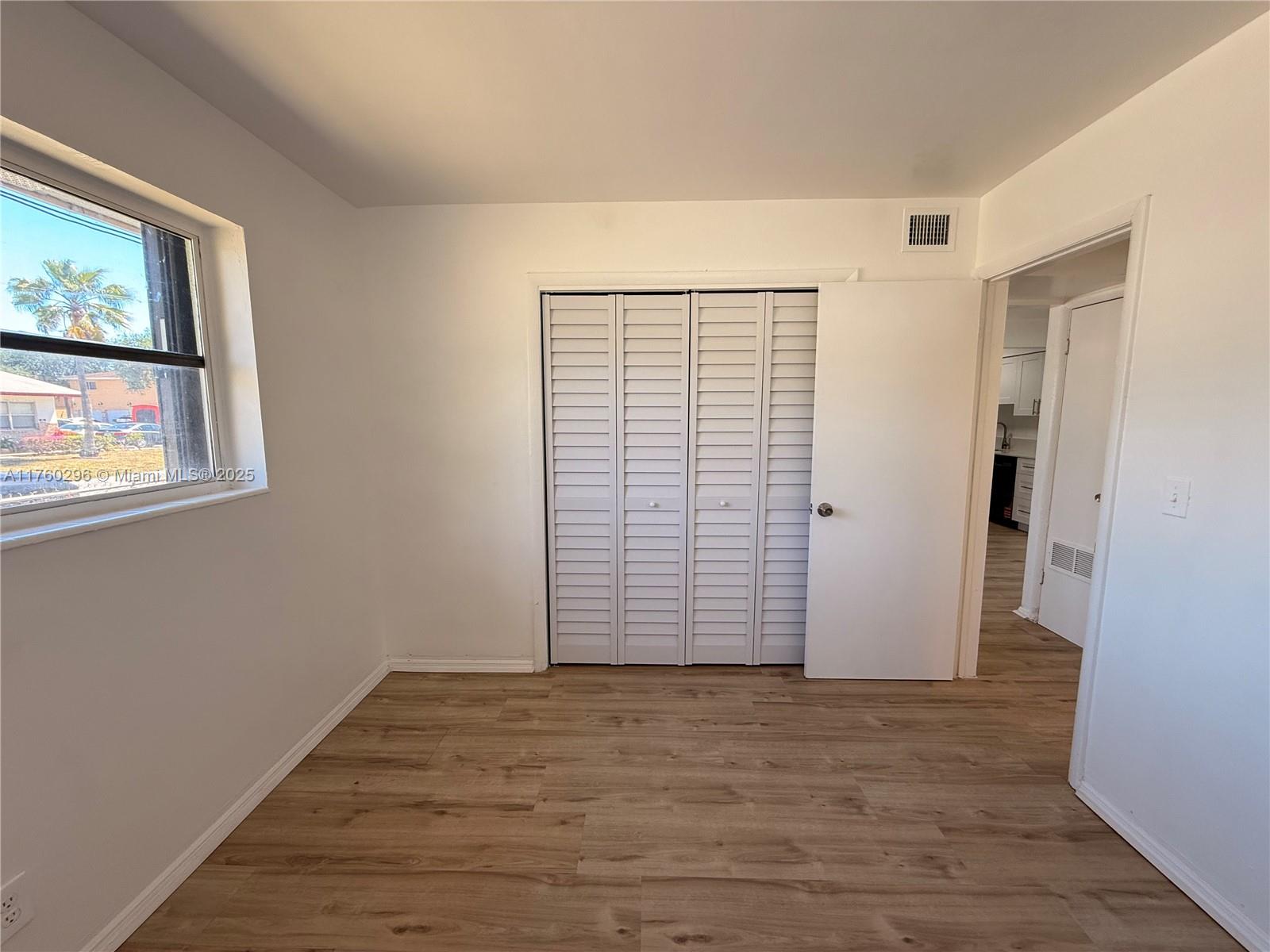 801 Southwest 7th Street, Unit B Pompano Beach, FL 33060 - Photo 13 of 20 a view of an empty room with wooden floor and a window